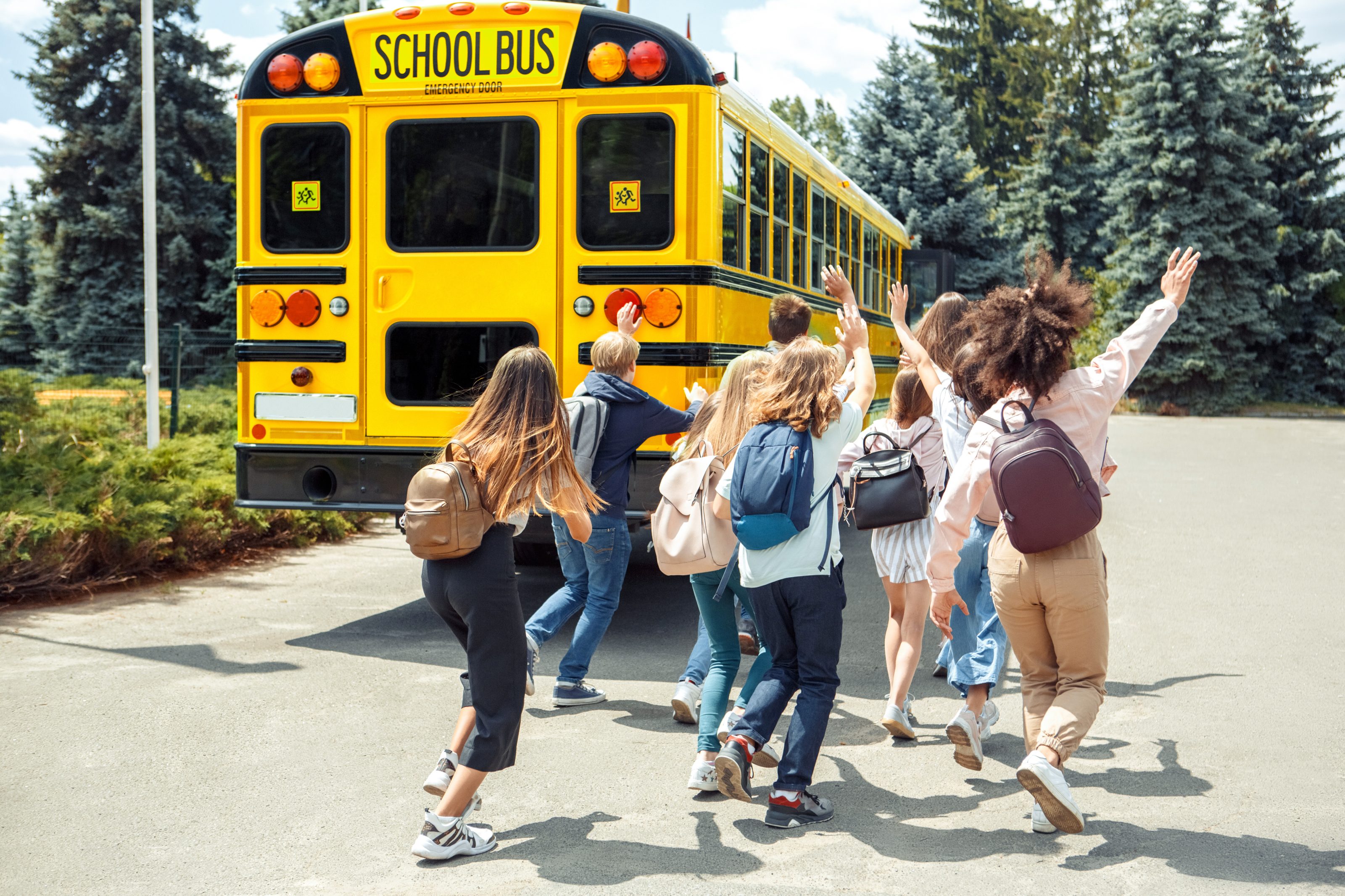 Being late. Classmates running to school bus back view waving to driver AdobeStock 294070188 scaled